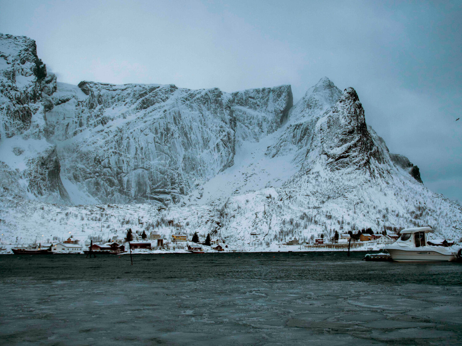 Snødekte fjell og kaldt og klart hav nord for Polarsirkelen